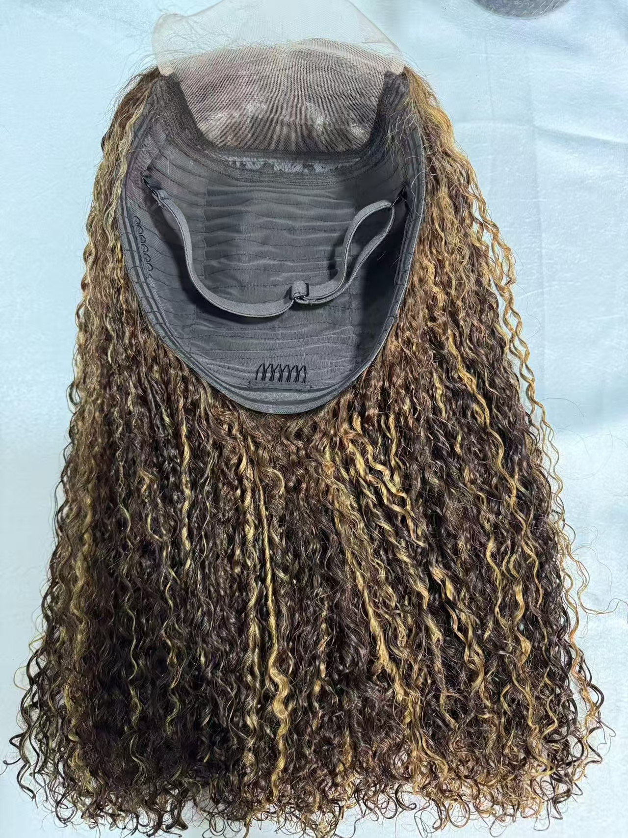 Mannequin head wearing a long curly lace front wig with brown and blonde highlights, 100% virgin human hair, 13x4 HD lace, natural pre-plucked hairline.