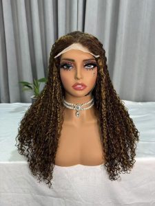 A mannequin head wearing a long curly human hair lace front wig with brown highlights and tight curls, styled for a natural look.